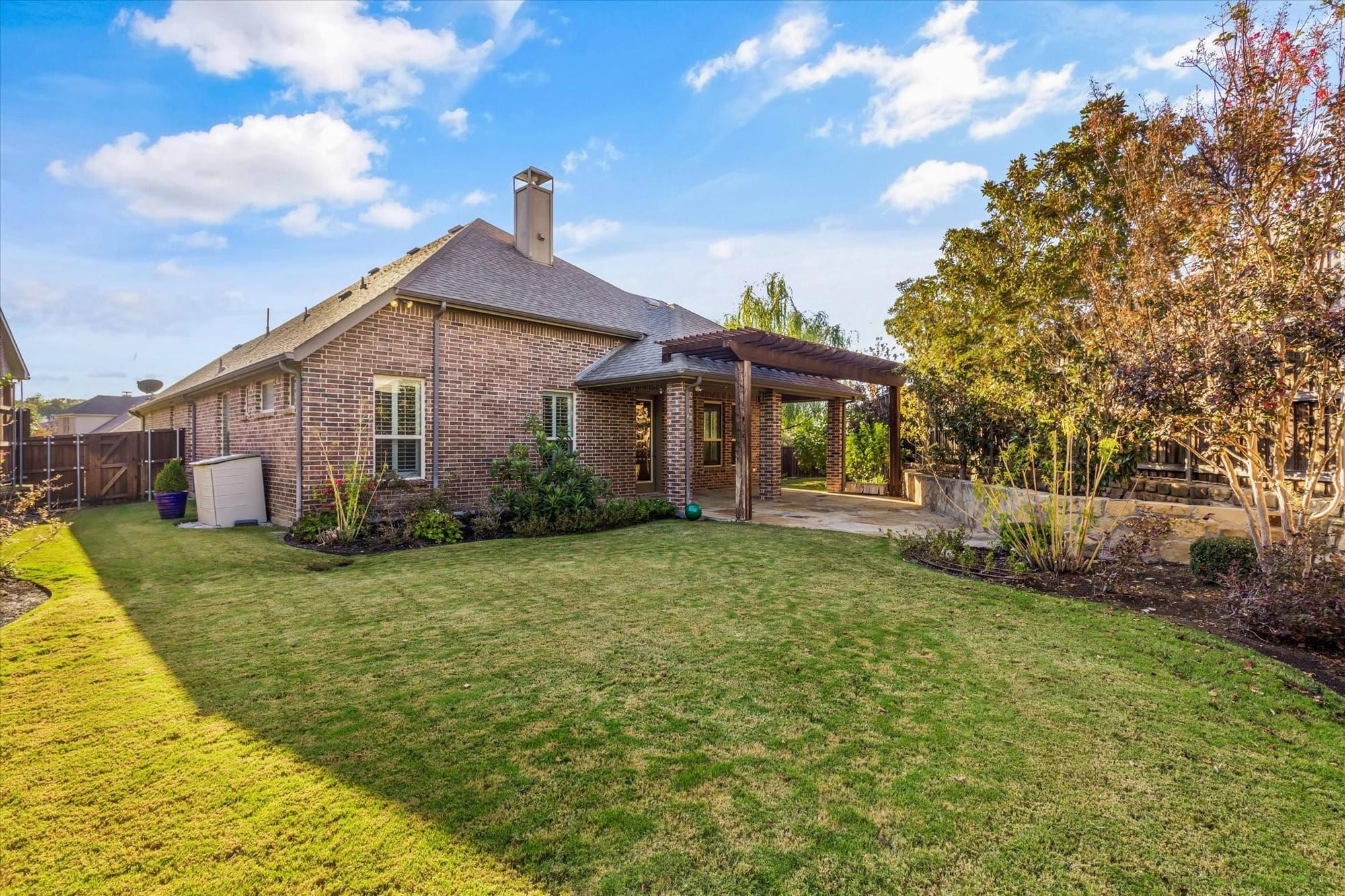 Covered stone patio and landscaped backyard at a home in the Riverhills neighborhood of Fort Worth, Texas.