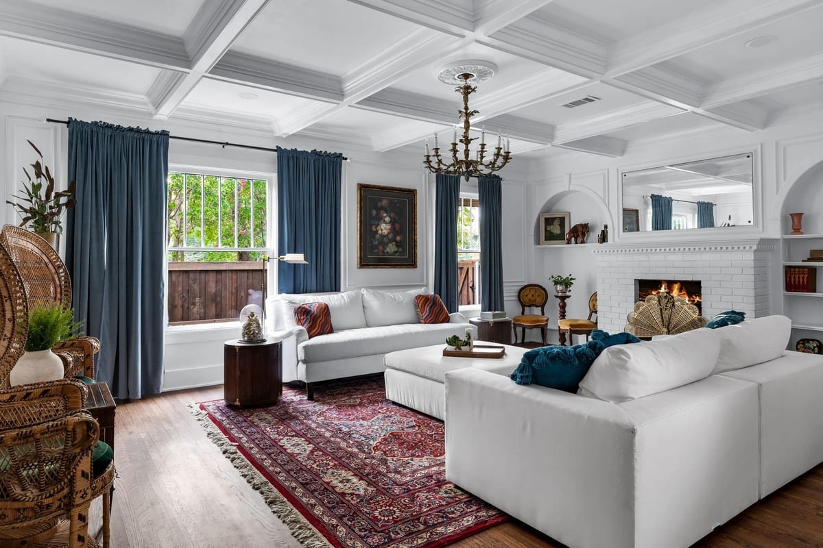 Residential living room interior styled with blue curtains, patterned rug, and a fireplace seating area, designed for everyday living.